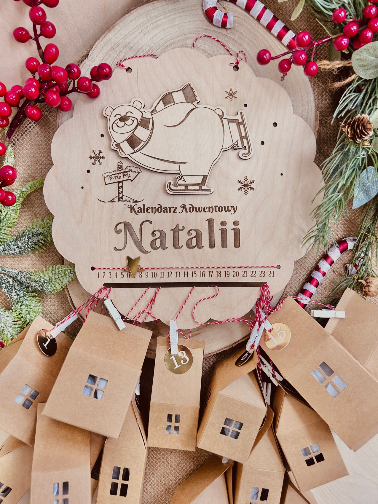 Kalendarz adwentowy w kształcie koła z misiem na łyżwach i domkami na sznurkach